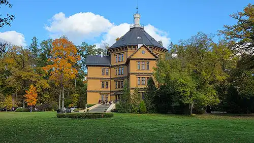 Pałac Radziwiłłów w Antoninie na tle jesiennego parku, widoczna główna fasada z rozległym trawnikiem.