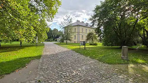Brukowana droga przez park prowadząca do tylnej elewacji Pałacu w Dobrzycy.