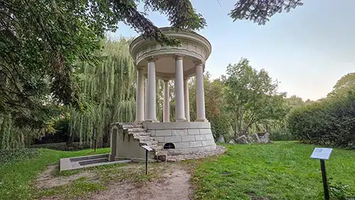 Klasycystyczna rotunda Monopter w parku w Dobrzycy. Widoczne kamienne schody i kolumny.